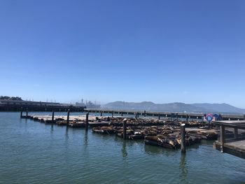 View of boats in calm lake against clear blue sky