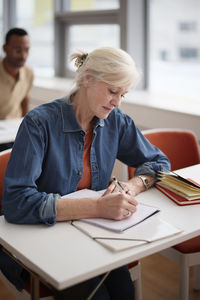 Mature woman making notes in class