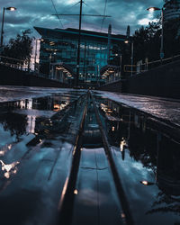 Railroad tracks in city against sky at dusk