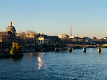 Bridge over river by buildings against sky in city