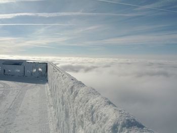 Snow covered observation point by cloudscape against sky