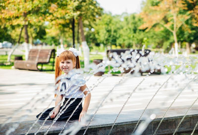 A little girl, an elementary school student, is playing merrily near the fountain .