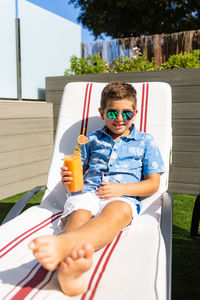 Funny boy drinking orange juice on a hammock