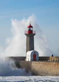 Lighthouse by sea against sky