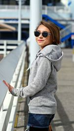 Side view of young woman wearing sunglasses standing outdoors