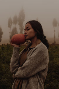 Side view of woman holding pumpkin