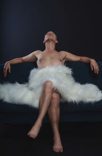 Portrait of shirtless man lying on black background