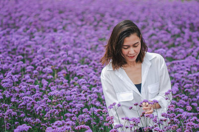 Beautiful woman standing amidst purple flowering plants