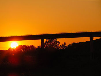 Silhouette bridge against orange sky during sunset