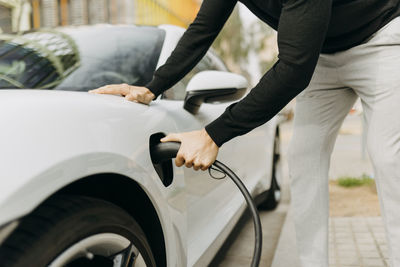 Man plugging electric charger in car at station