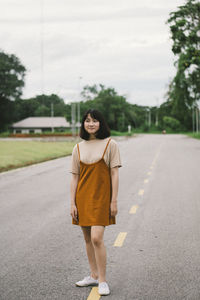Portrait of young woman standing on road in city