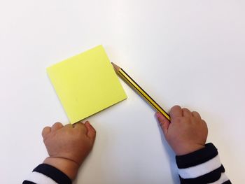 Close-up of hand holding paper against white background