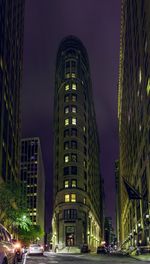 Illuminated city street and buildings against sky at night