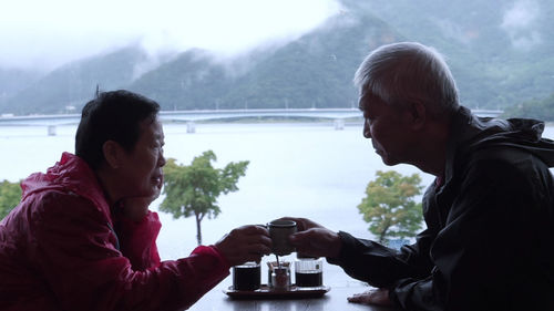 Couple toasting coffee cups while sitting at table