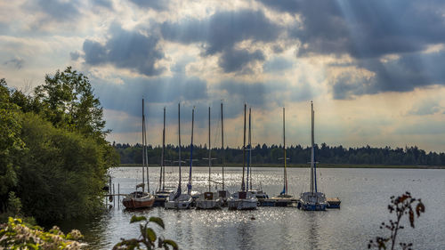 Sailboats moored in sea against sky