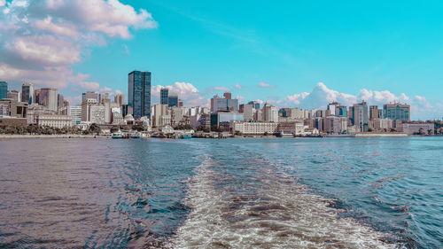 Sea by city buildings against sky