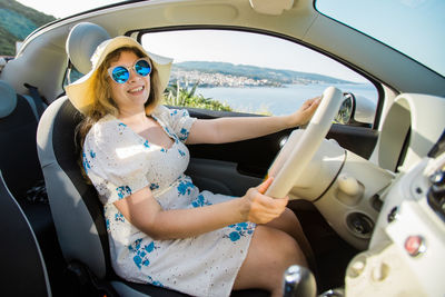Portrait of young woman using phone while sitting in car