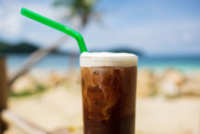 Close-up of beer glass on beach