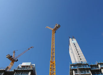 Low angle view of crane against clear blue sky