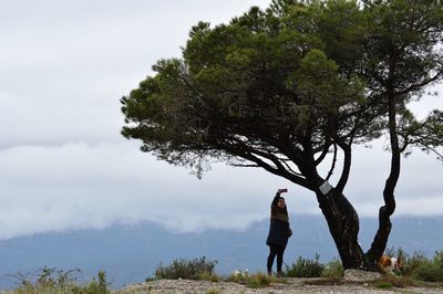 Woman taking selfie by tree against sky