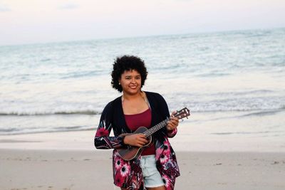 Portrait of a young man playing guitar on beach