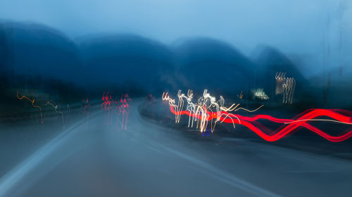 Light trails on road against sky at night