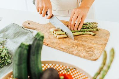 Close up of female hands cutting asparagus on a cutting board