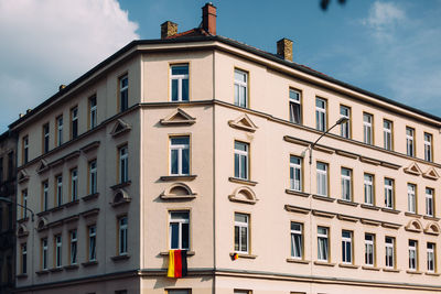 Low angle view of residential building with german flag against sky