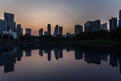 Reflection of buildings in lake against sky during sunset