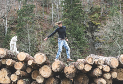 Full length of man climbing on log in forest