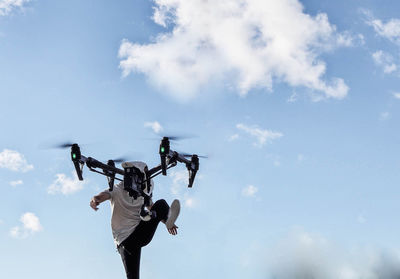 Low angle view of man with drone against sky