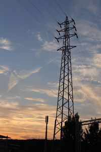 Low angle view of silhouette electricity pylon against sky during sunset