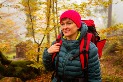 Happy young woman standing by tree during autumn