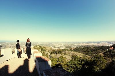 Rear view of people looking at view against sky