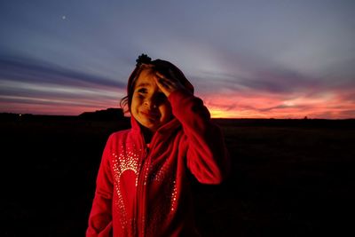 Girl crying while standing at park against sky during sunset