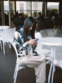 Young woman using mobile phone while sitting at restaurant