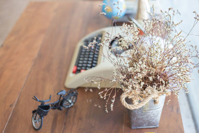 Flower vase by typewriter on wooden table
