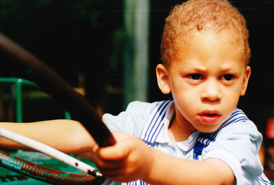 Thoughtful boy holding steering wheel while looking away