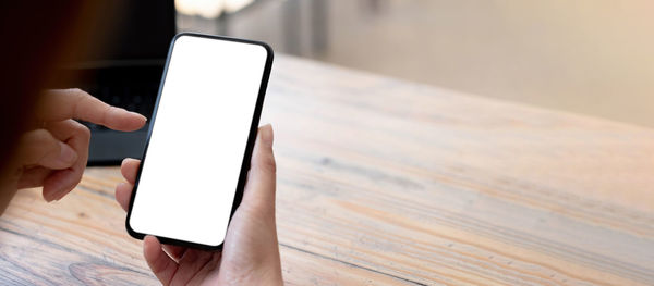 Midsection of man using mobile phone on table