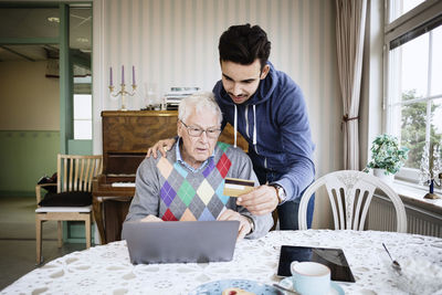 Caretaker and senior man using credit card to shop online