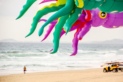 Colorful kites flying over beach against sky