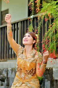 Young woman looking away while standing against plants