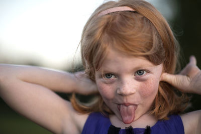 Close-up of girl sticking out tongue at park
