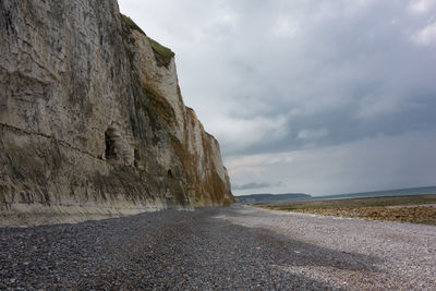 Road amidst rocks and sea against sky