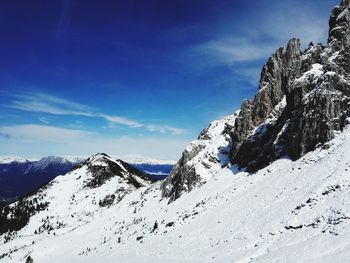 Low angle view of snowcapped mountains against blue sky