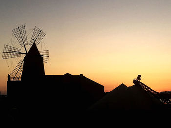 Silhouette traditional windmill against sky during sunset