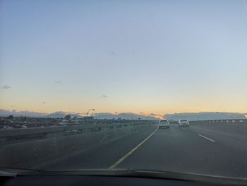 Cars on road against sky seen through car windshield