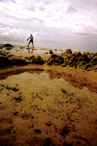 Silhouette man walking on sand at beach against sky