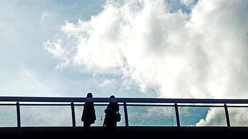 Silhouette people standing by railing against sky