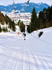 Mid adult man snowboarding on snow covered field against mountain